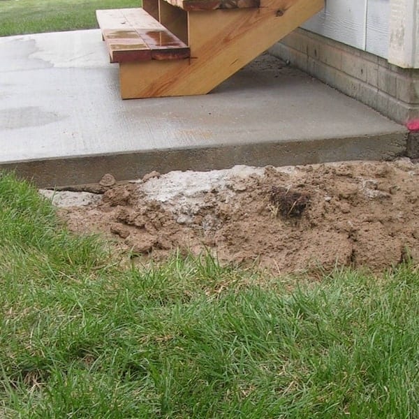 Concrete patio step after void filling, showing repaired and stabilized area with fresh soil around the base.