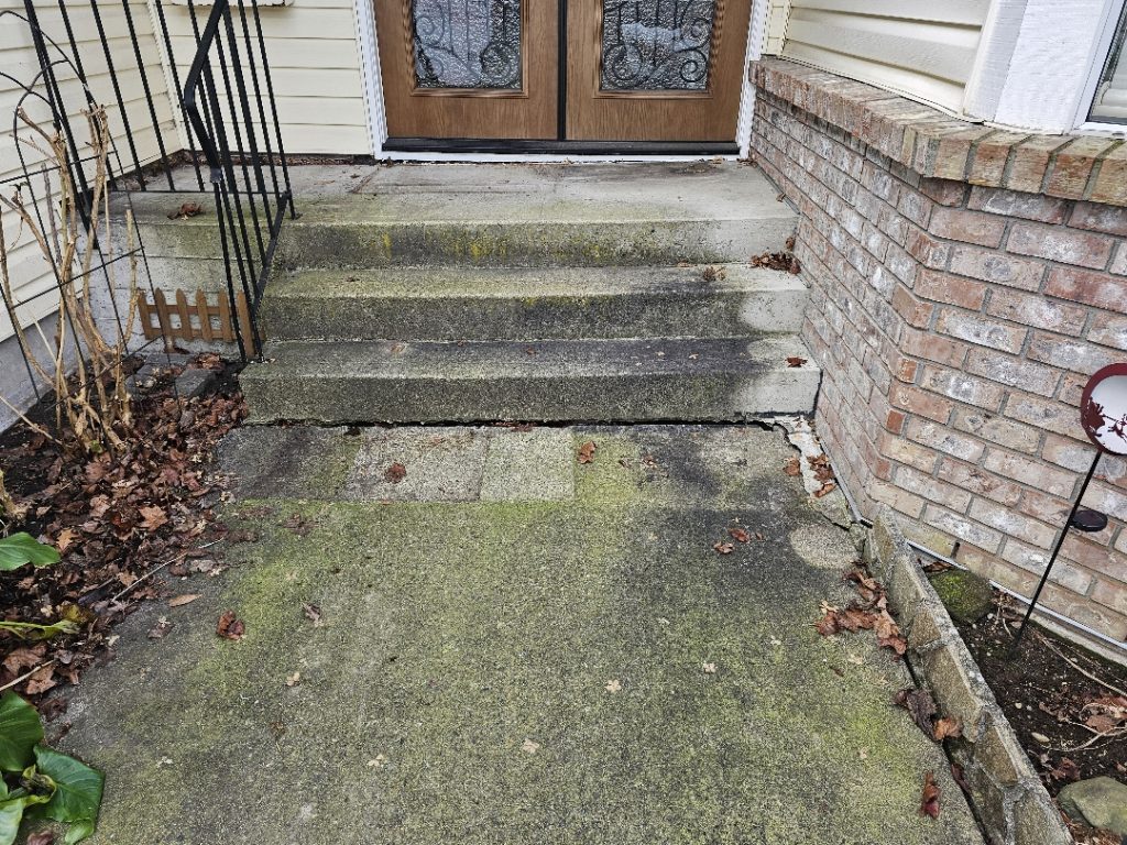 front entry of the house sloped to the left and sunken walkway leading to the steps